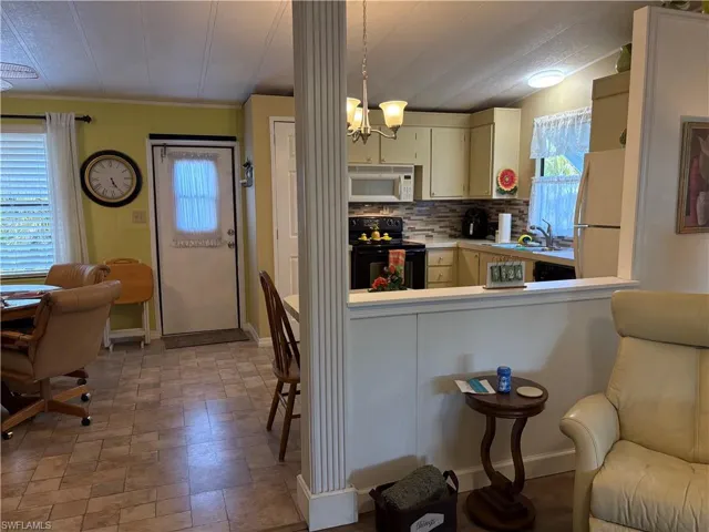 Kitchen with decorative light fixtures, sink, decorative backsplash, white appliances, and an inviting chandelier
