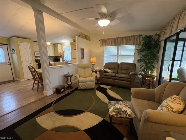 Living room featuring vaulted ceiling with beams, light hardwood / wood-style floors, decorative columns, and ceiling fan