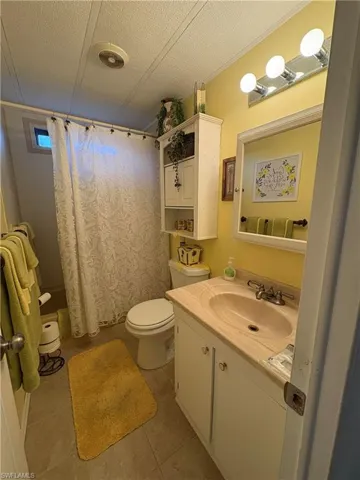 Bathroom with tile patterned flooring, vanity, a textured ceiling, and toilet