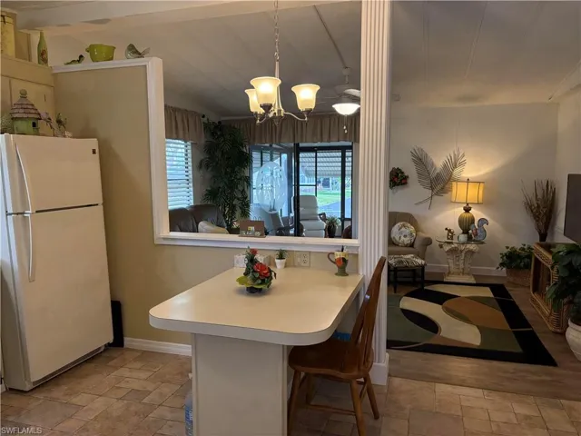 Kitchen with pendant lighting, a breakfast bar area, white refrigerator, vaulted ceiling, and a chandelier