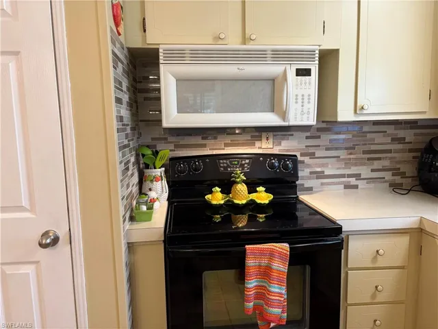 Kitchen featuring tasteful backsplash, black electric range, and cream cabinetry