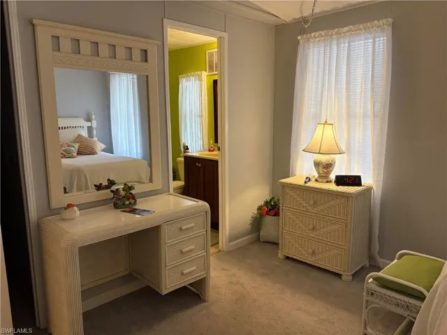 Bedroom with connected bathroom and light colored carpet