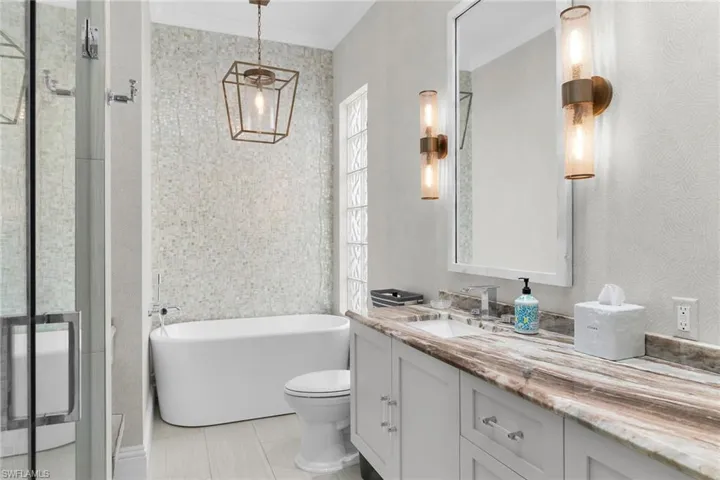 Full bathroom with a freestanding bath, vanity, a shower stall, wallpapered walls, and light tile patterned floors