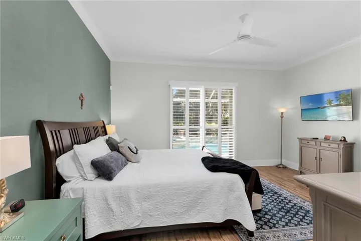 Bedroom with wood finished floors, crown molding, and ceiling fan