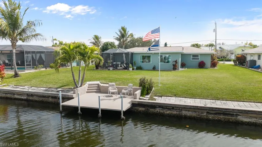 Dock area featuring a lawn, a water view, a sunroom, a patio area, and glass enclosure