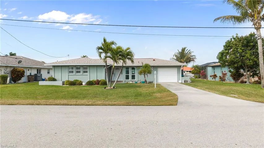 Ranch-style house featuring a front yard, concrete driveway, and an attached garage