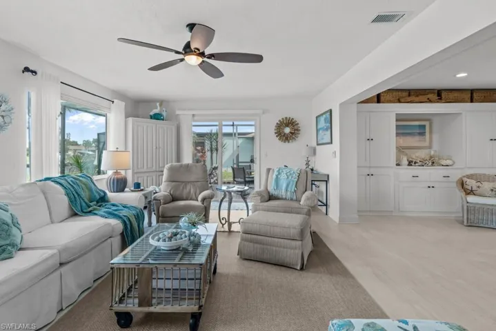 Living area with light wood-type flooring, plenty of natural light, and a ceiling fan