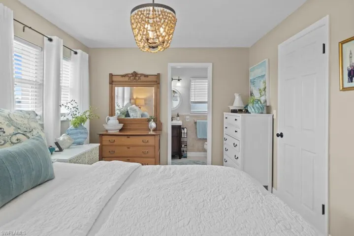 Bedroom featuring hanging lights and connected bathroom