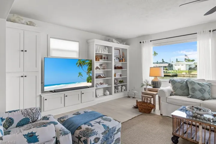 Living room with light wood-style floors, a ceiling fan, and healthy amount of natural light