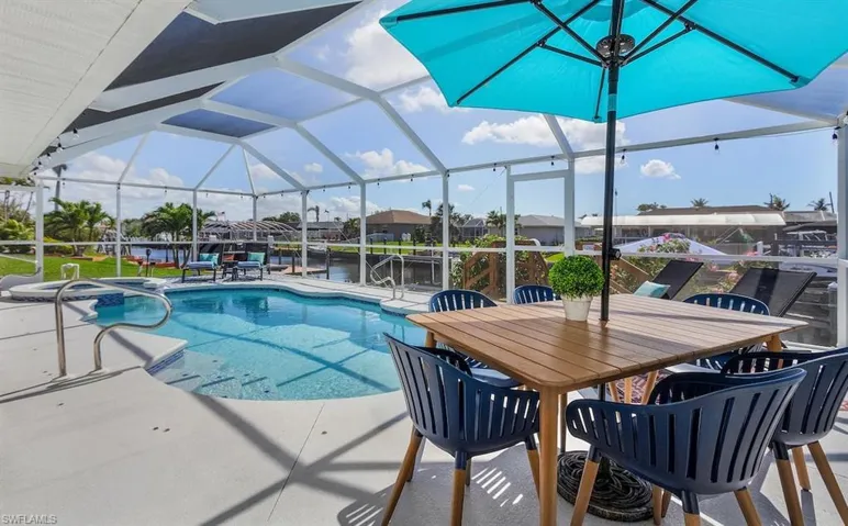 View of swimming pool featuring a lanai, a pool with connected hot tub, outdoor dining area, and a patio