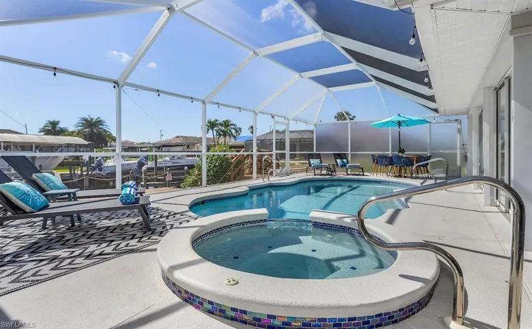 View of pool featuring a pool with connected hot tub, glass enclosure, and a patio
