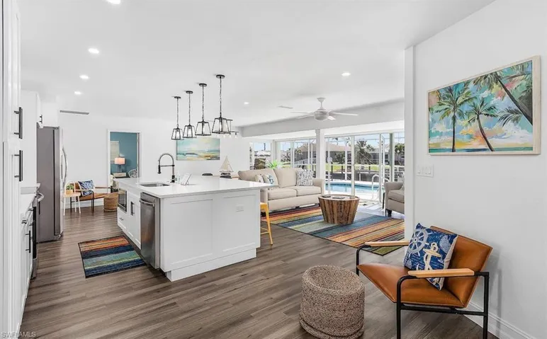 Kitchen featuring dark wood-style flooring, stainless steel appliances, open floor plan, white cabinetry, and a sink