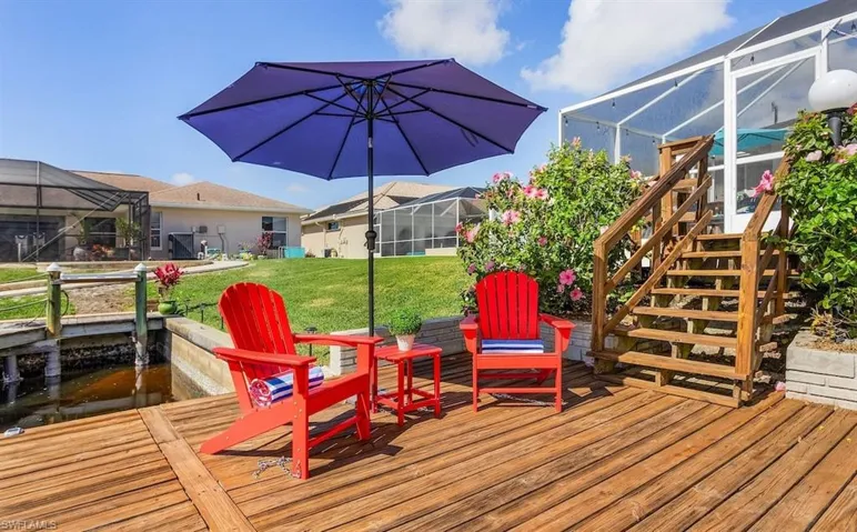 Wooden deck featuring glass enclosure, stairway, and a yard