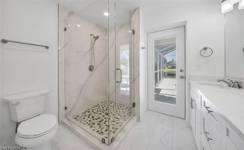 Full bath with toilet, marble finish floor, a marble finish shower, and vanity