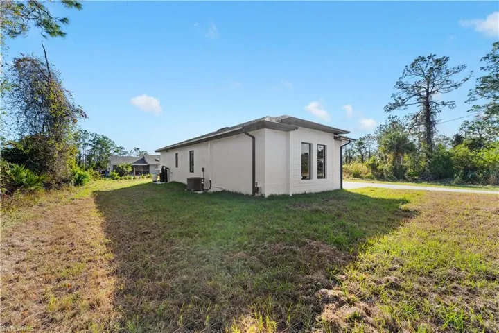 View of property exterior featuring central AC unit and a lawn