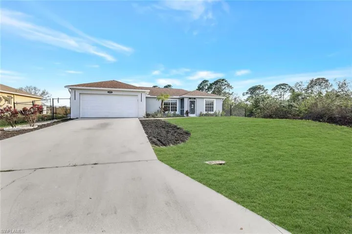 Single story home featuring stucco siding, concrete driveway, an attached garage, a front yard, and fence