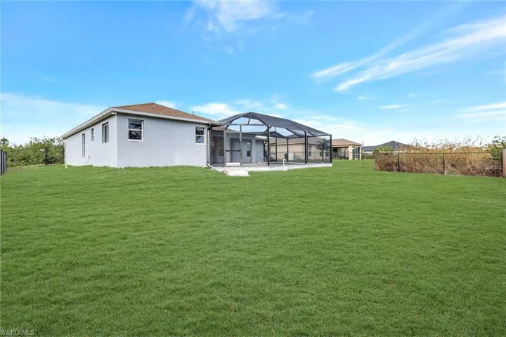 Back of house featuring a patio, a lawn, a lanai, and stucco siding