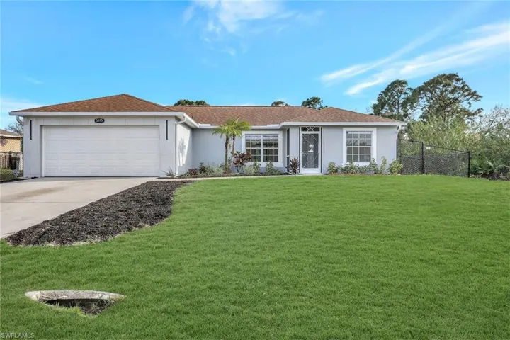 Ranch-style house with a front yard, concrete driveway, an attached garage, and stucco siding
