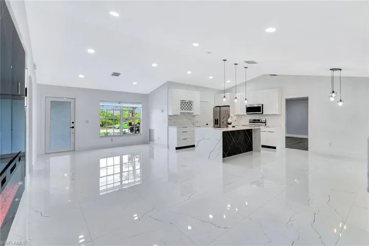 Kitchen featuring pendant lighting, a large island, light countertops, appliances with stainless steel finishes, and white cabinetry