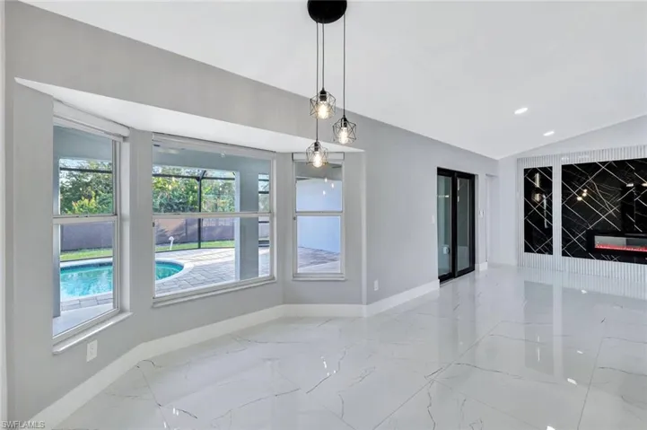 Unfurnished dining area featuring vaulted ceiling, marble finish floor, recessed lighting, and baseboards