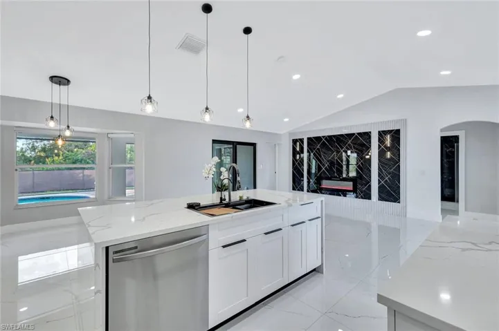 Kitchen featuring pendant lighting, white cabinetry, a sink, an island with sink, and dishwasher