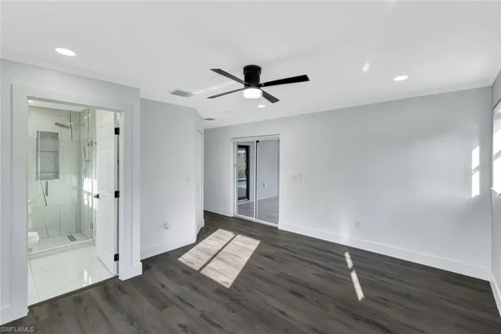 Unfurnished bedroom featuring dark wood-style floors, visible vents, ornamental molding, and baseboards
