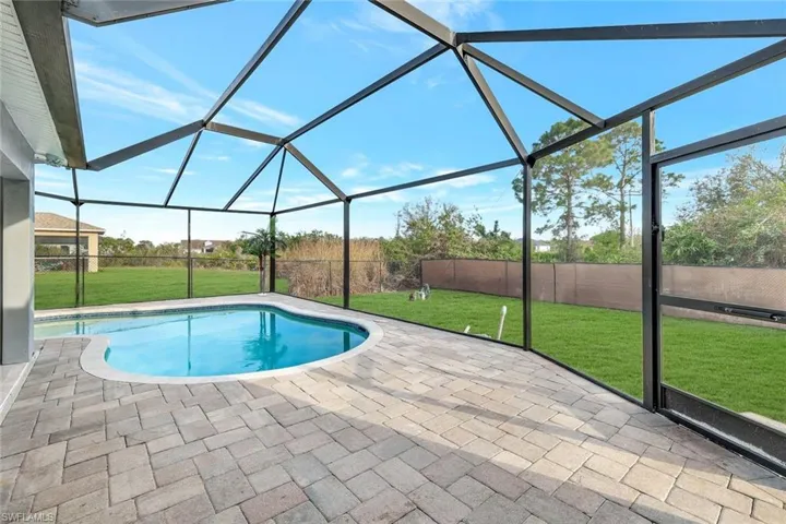 View of swimming pool featuring a fenced in pool, a lawn, a patio area, glass enclosure, and a fenced backyard