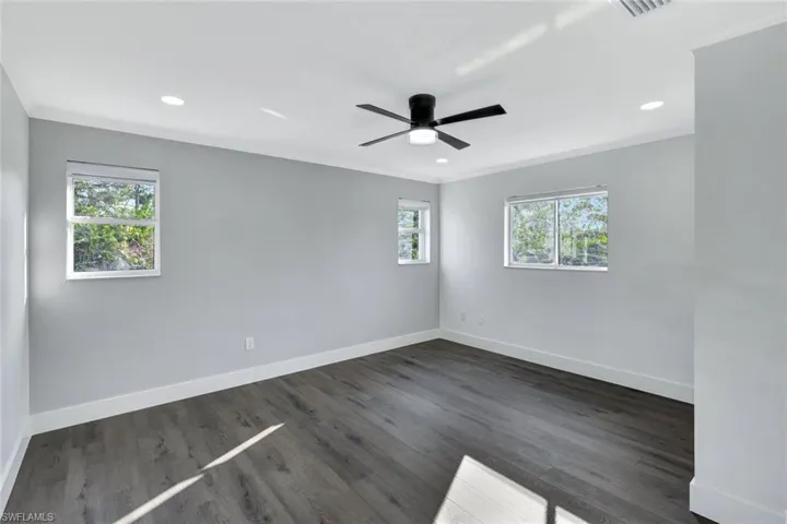 Spare room featuring dark wood-style flooring, crown molding, recessed lighting, a ceiling fan, and baseboards