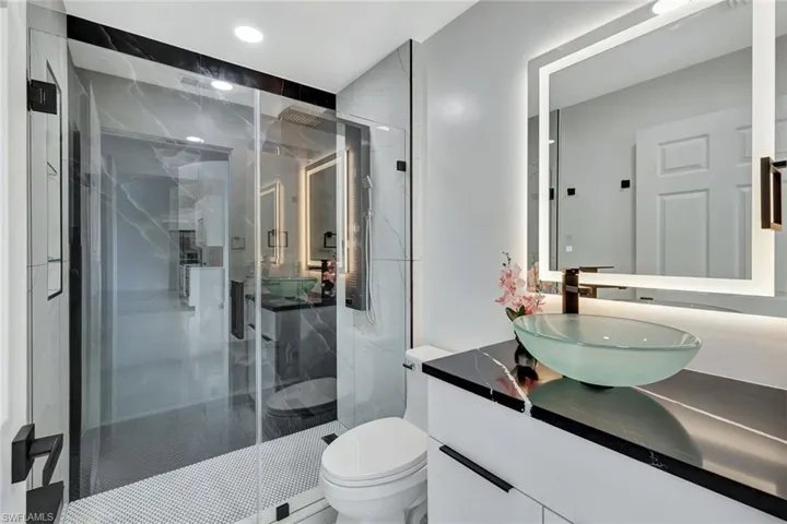 Bathroom featuring recessed lighting, a marble finish shower, vanity, and toilet