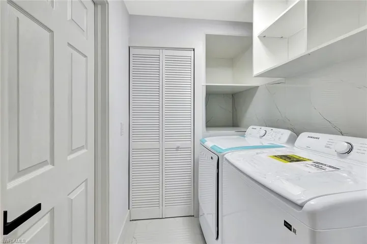 Laundry room featuring marble finish floor, laundry area, and separate washer and dryer