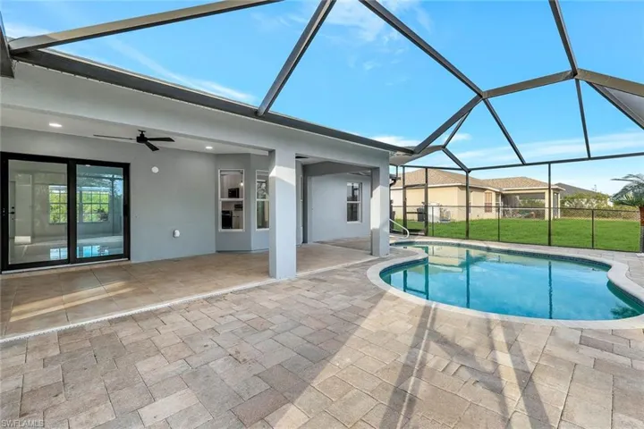 Outdoor pool featuring a lanai, a patio area, a lawn, and a ceiling fan