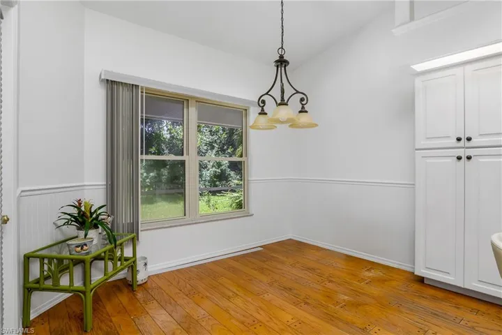 Dining area featuring vaulted ceiling, light wood-type flooring, and a chandelier