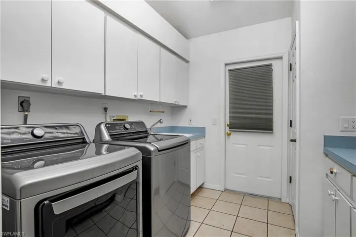 Clothes washing area with sink, cabinets, independent washer and dryer, and light tile patterned floors