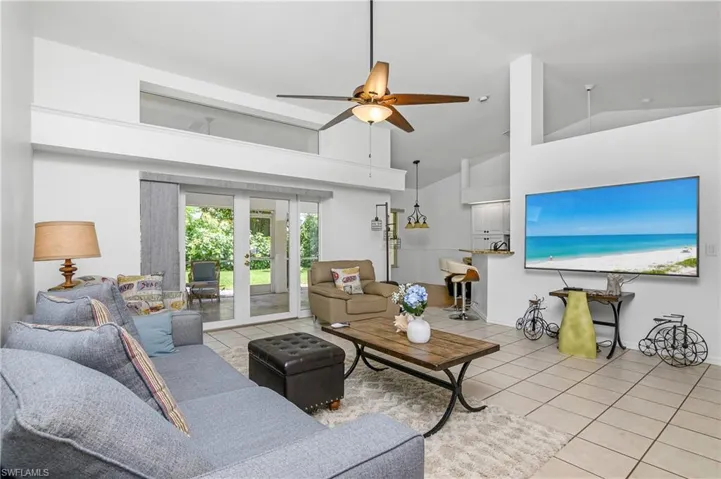 Living room featuring french doors, light tile patterned flooring, ceiling fan, and high vaulted ceiling
