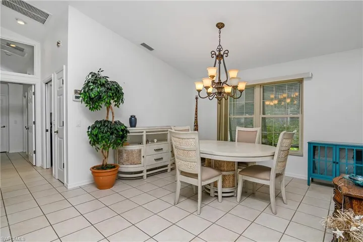 Tiled dining area with a notable chandelier and vaulted ceiling