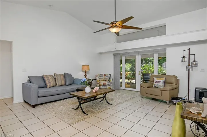 Tiled living room featuring french doors, ceiling fan, and high vaulted ceiling