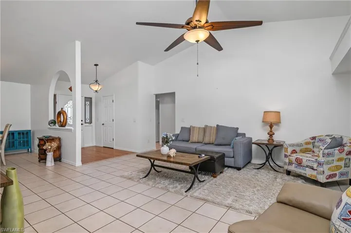 Tiled living room featuring high vaulted ceiling and ceiling fan