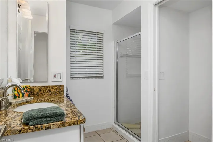 Bathroom featuring a shower with shower door, vanity, and tile patterned flooring