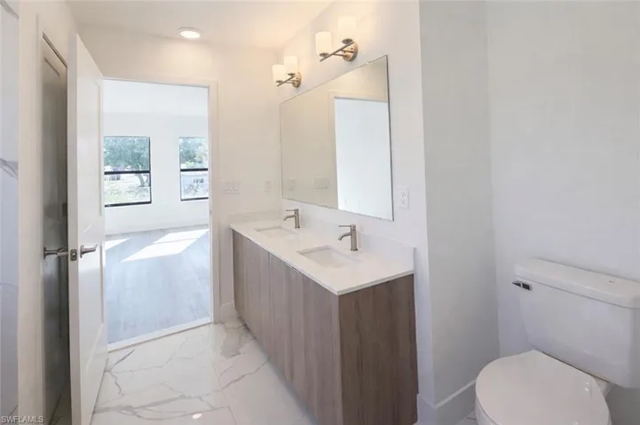 Bathroom featuring double vanity and light marble finish floors