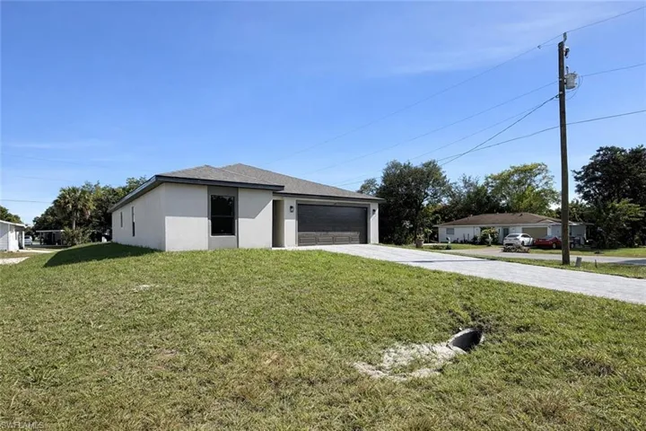View of front of property with driveway, a front lawn, a garage, and stucco siding