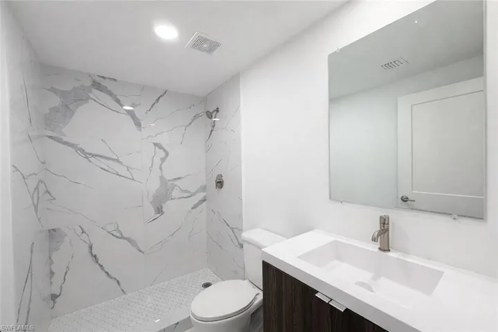 Full bathroom featuring a marble finish shower and vanity