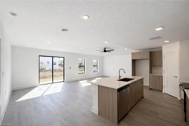 Kitchen with modern cabinets, a center island with sink, open floor plan, dishwasher, and a textured ceiling