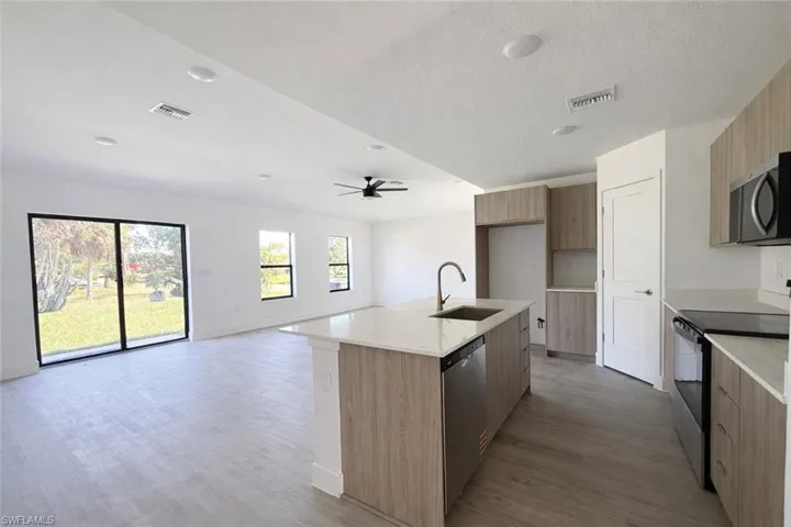 Kitchen featuring stainless steel appliances, light stone countertops, modern cabinets, a kitchen island with sink, and a textured ceiling