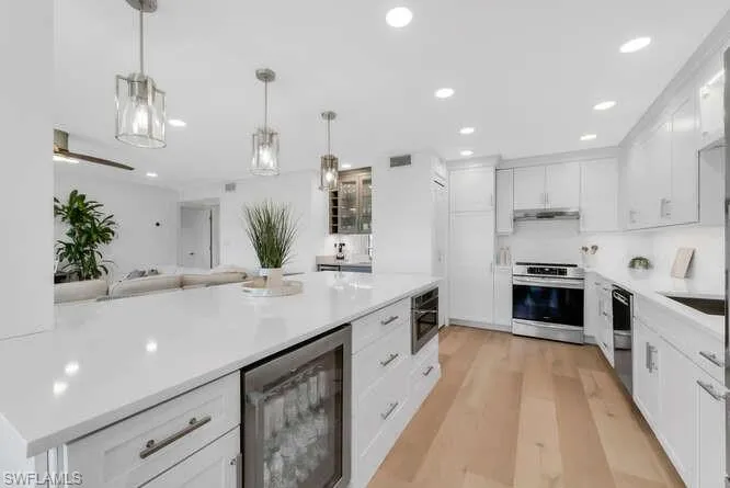 Kitchen with beverage cooler, stainless steel electric range oven, dishwasher, white cabinetry, and under cabinet range hood