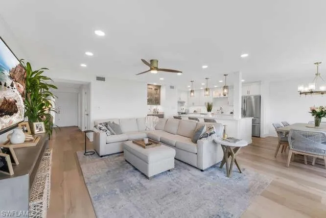 Living room featuring light wood-style floors, a ceiling fan, a chandelier, and recessed lighting
