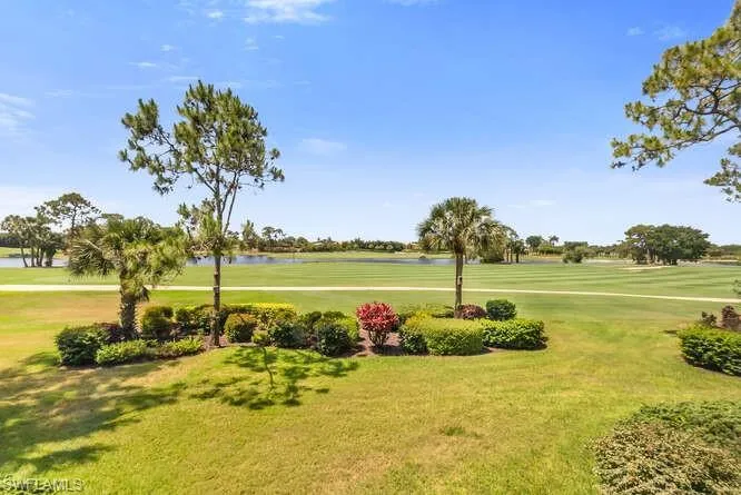 View of property's community with golf course view, a water view, and a lawn