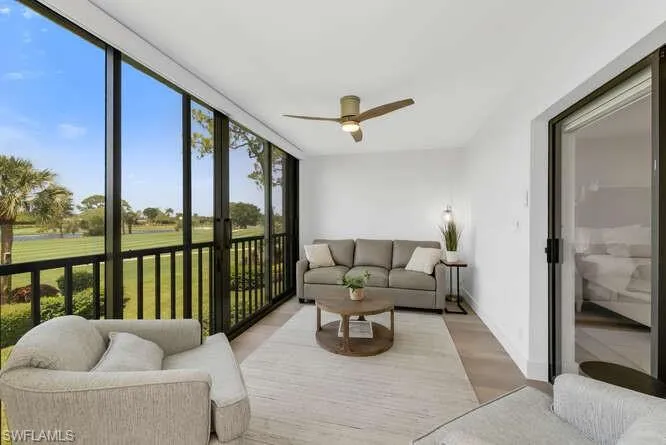 Sunroom featuring expansive windows, wood finished floors, view of golf course, and baseboards
