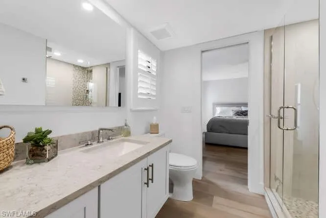 Bathroom featuring a stall shower, wood finished floors, toilet, and recessed lighting