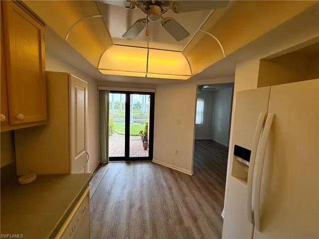 Kitchen area featuring a raised ceiling, ceiling fan, and light wood-style flooring