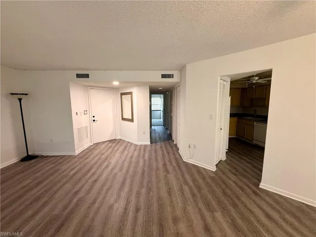 Unfurnished living room featuring dark wood-style flooring, a textured ceiling, and a ceiling fan